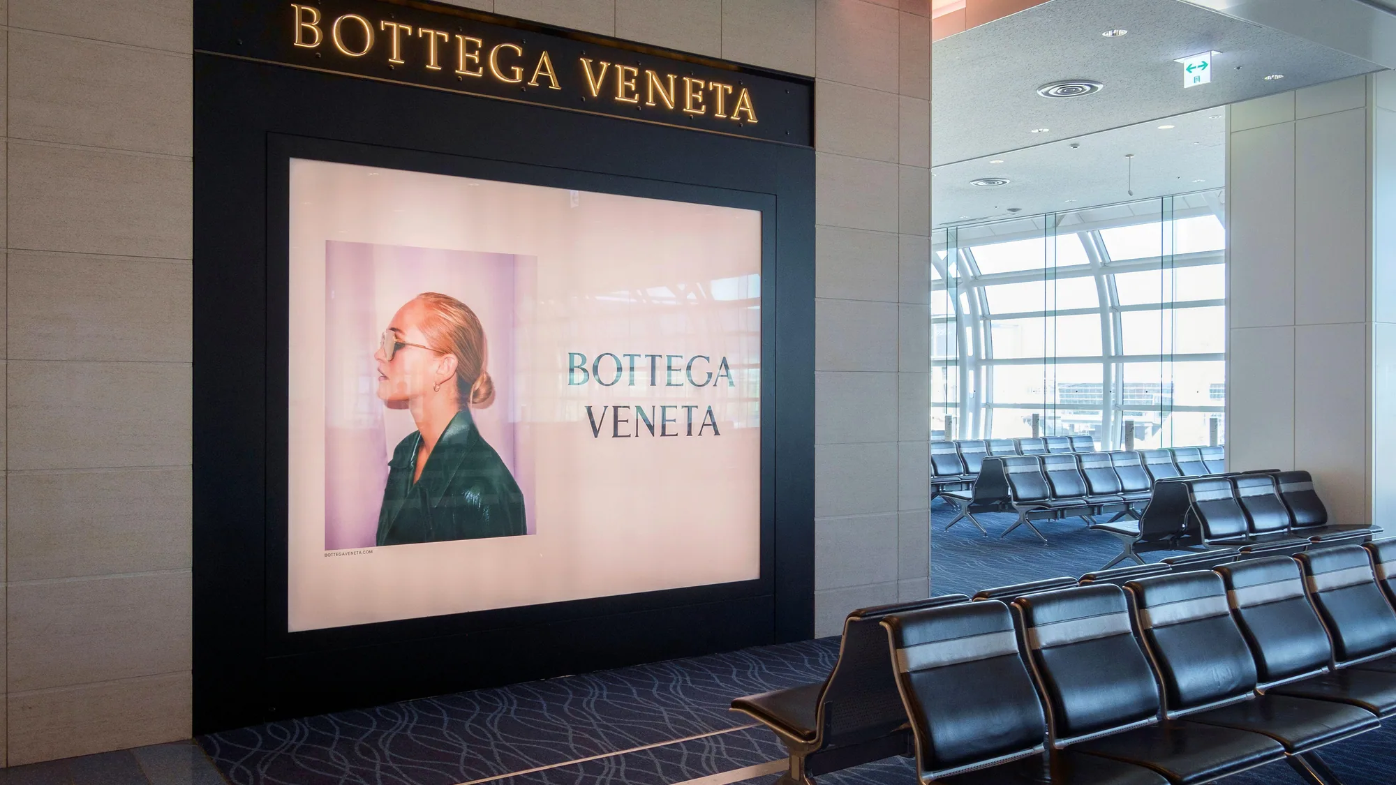 Airport advertising at Munich Airport in Germany: departure boards fill the hall beside a bright pink digital advertisement and an information desk.