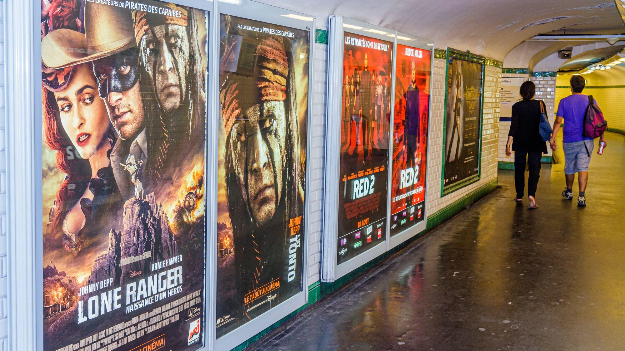 Underground advertising in Paris, in France: a tiled Paris Metro corridor is lined with posters for The Lone Ranger and RED 2.