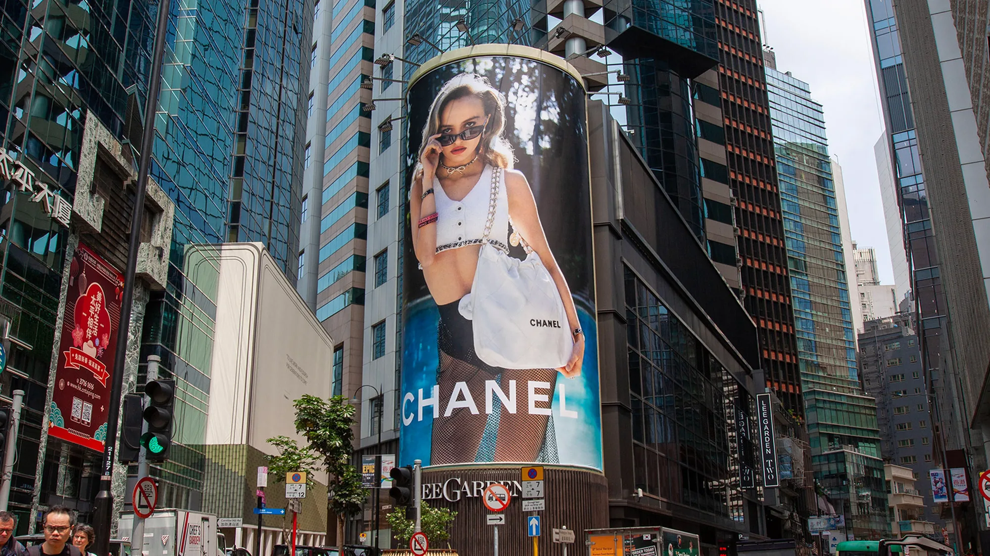 Building banner advertising in Hong Kong: a curved Chanel banner shows a model with a white Chanel tote, above a Lee Garden sign.