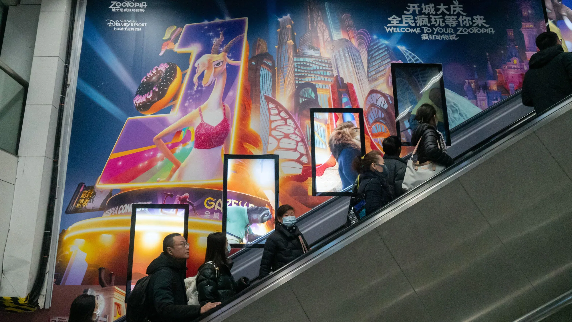 Underground advertising: commuters on an escalator pass a Shanghai Disney Resort poster that reads Welcome to your Zootopia.