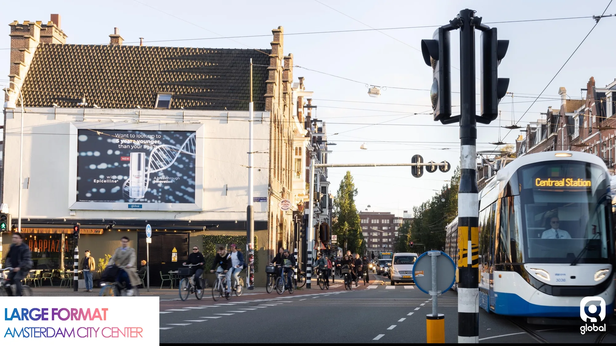 Large format billboard advertising in Amsterdam, in the Netherlands: a wall billboard with a line graph faces the street beside a tram headed for Centraal Station.