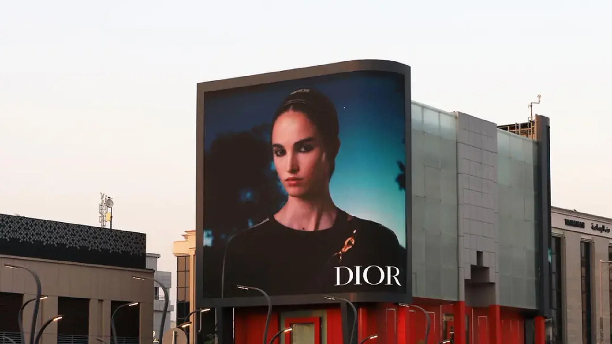 Digital billboard advertising in Saudi Arabia: a large screen shows a Dior portrait of a woman in black.