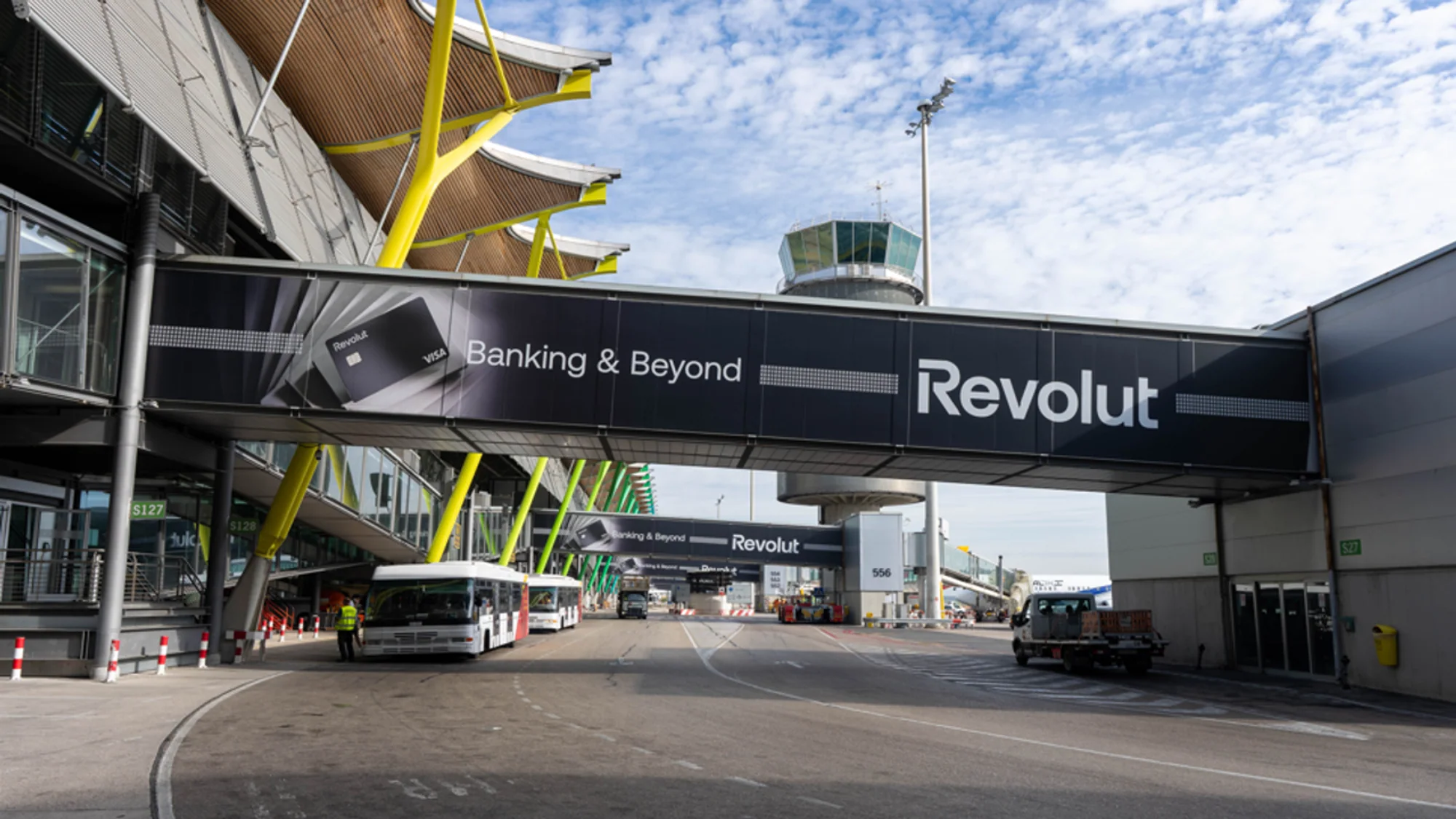 Bridge banner advertising at Madrid airport in Spain: a Revolut banner reading Banking and Beyond spans a roadway, with the control tower behind it.