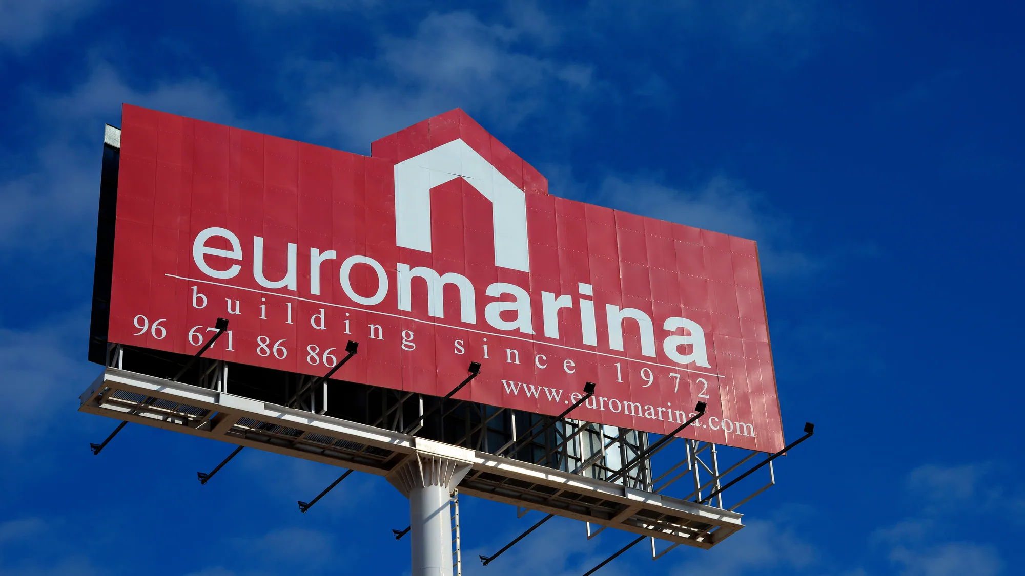 Billboard advertising outside Ciudad Quesada, Spain: a large red Euromarina board, reading building since 1972, stands against a blue sky.