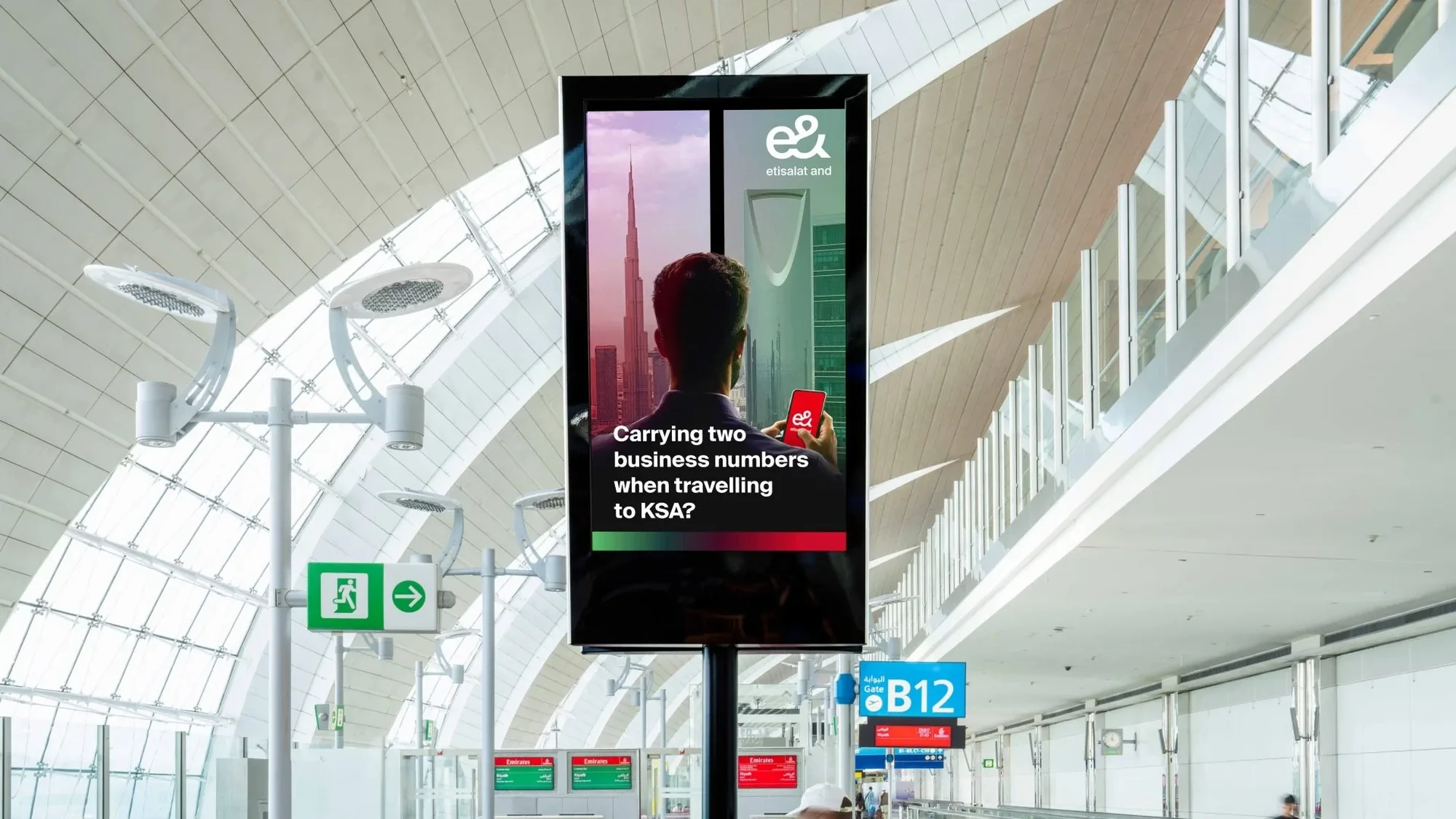 Programmatic airport advertising in the UAE: a screen advertises e& and Etisalat for travellers carrying two business numbers to KSA.