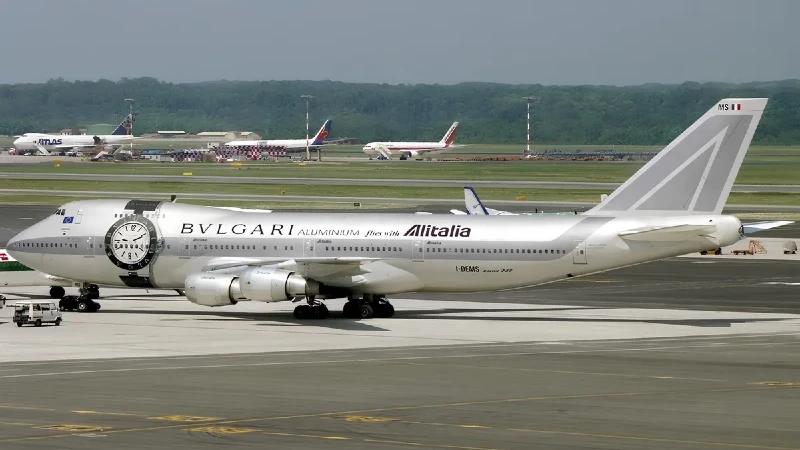 Aircraft advertising: a white Alitalia Boeing 747 in Bvlgari Aluminium livery, with a watch face on the nose, stands on the apron.