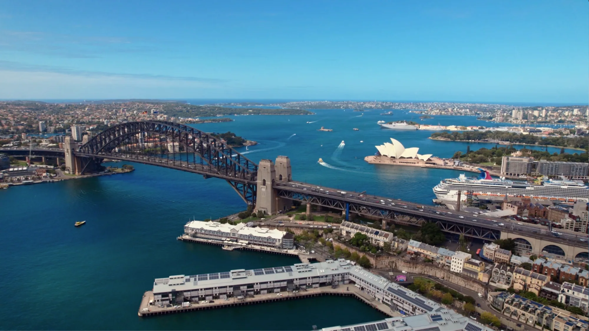 Sydney Harbour Bridge and the Opera House are seen from the air, with a cruise ship in the harbour.