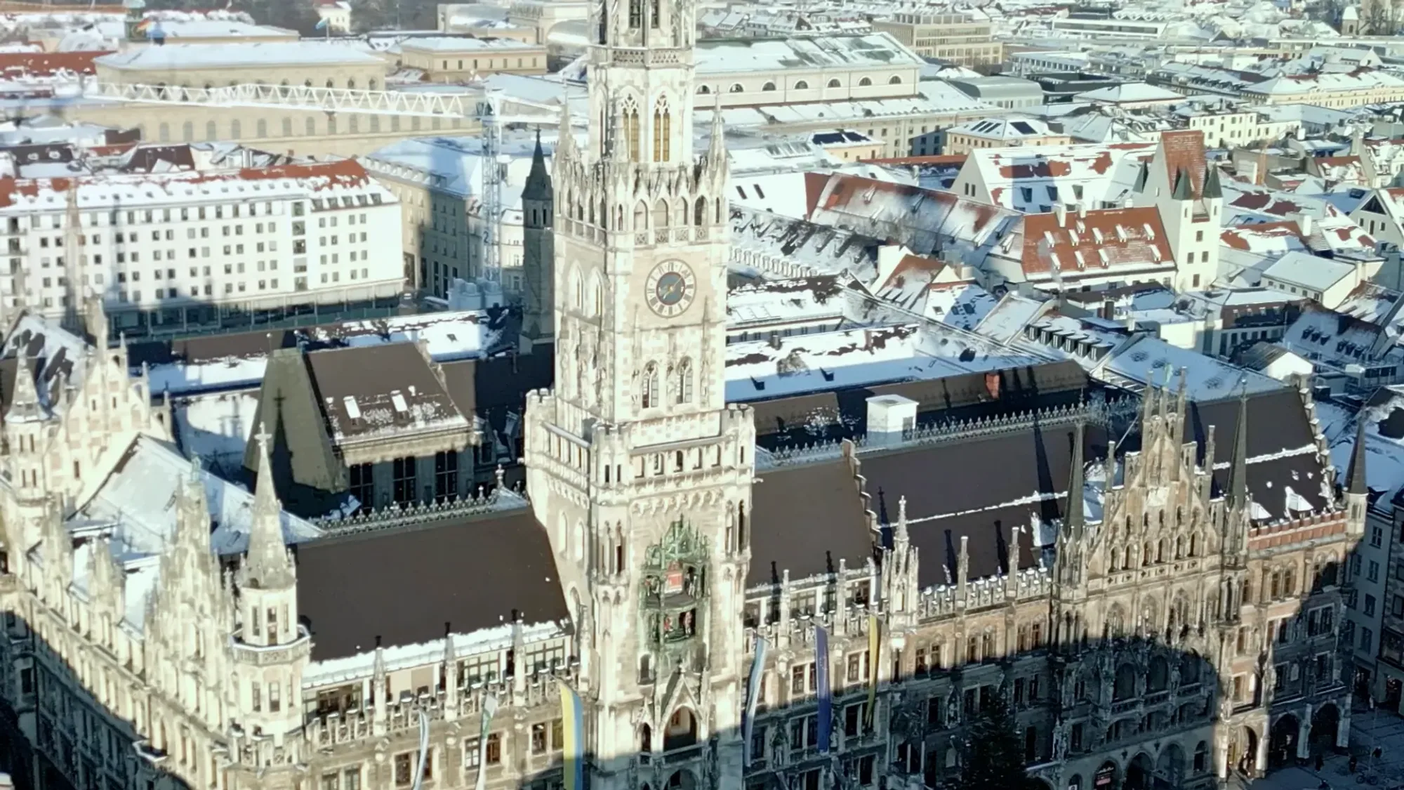 Snow covers the clock tower and Gothic roofs of Munich's New Town Hall.
