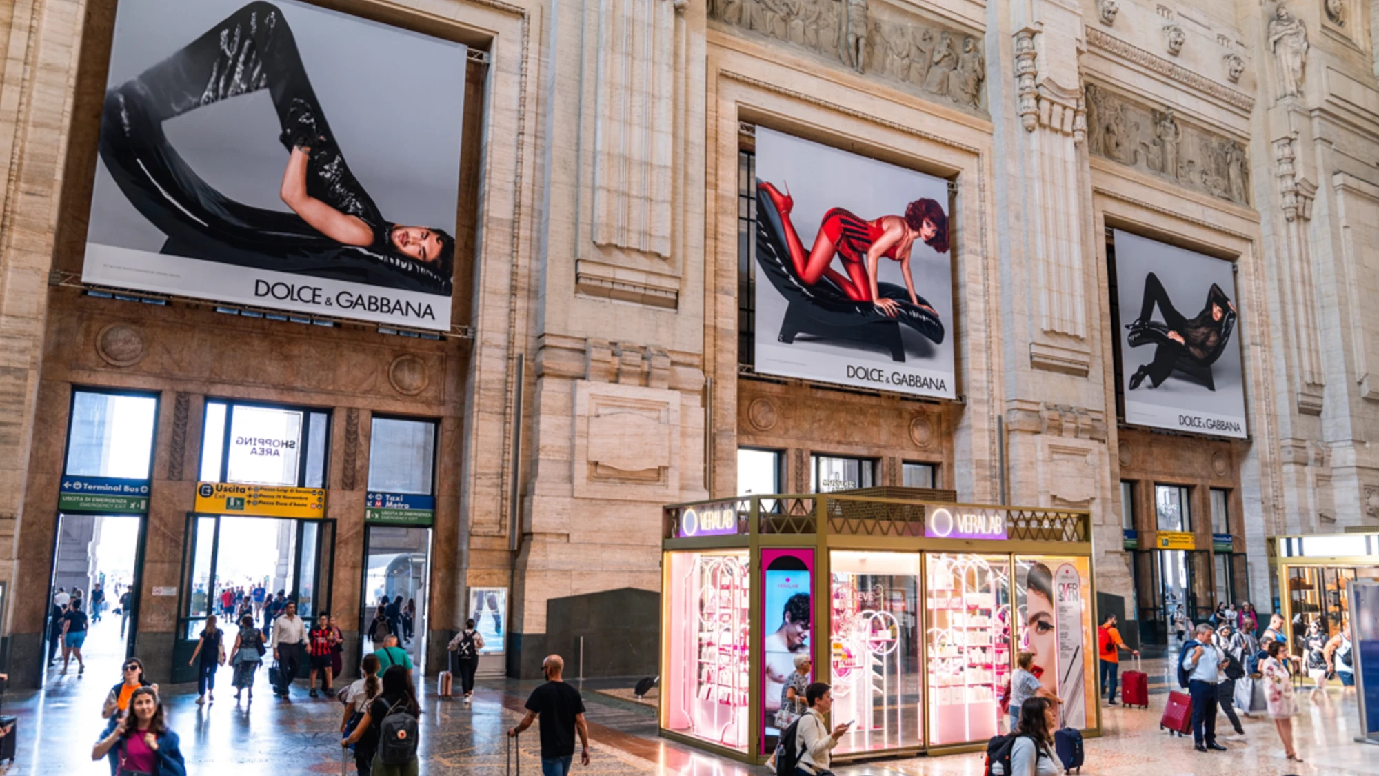 Billboard advertising in Italy: a large Prada board of a woman in sunglasses faces a crowded square.