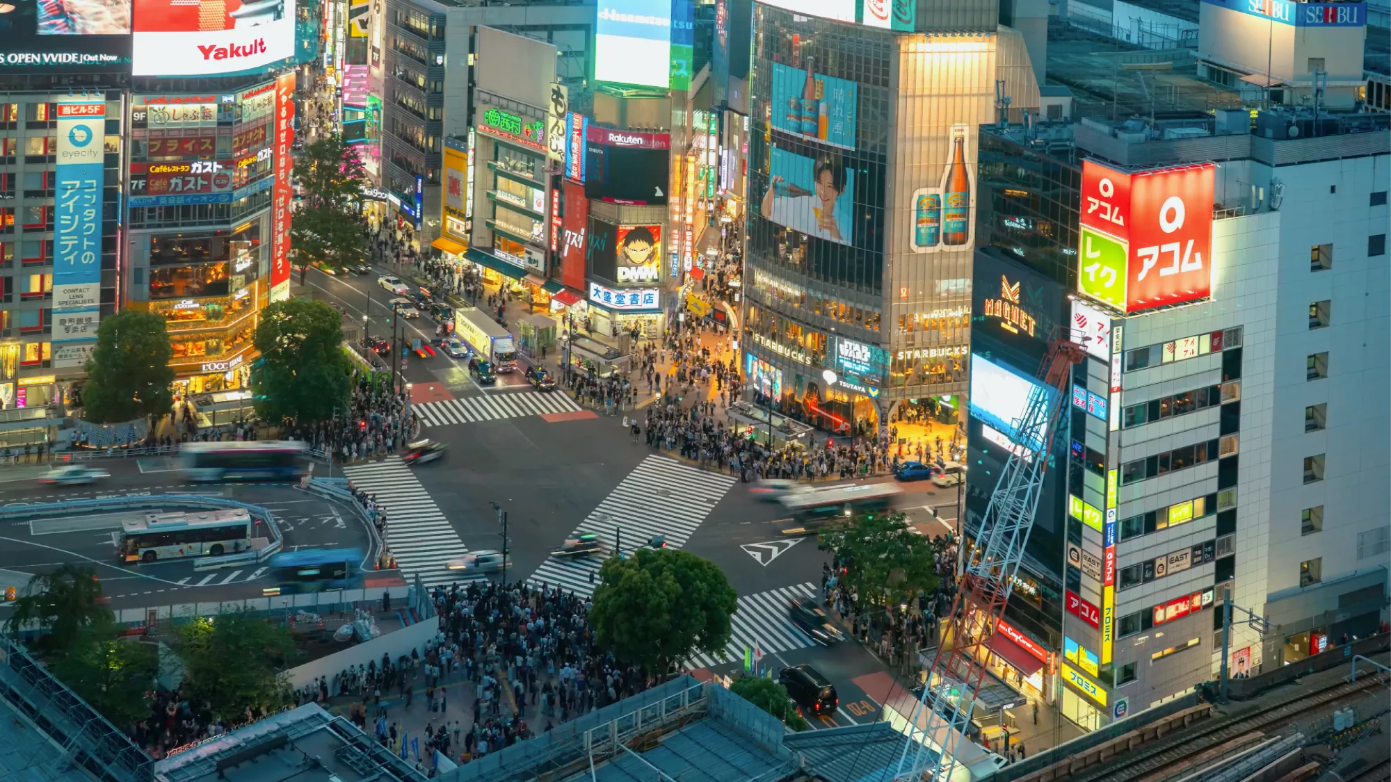 Digital billboard advertising at Shibuya Crossing in Tokyo, Japan: crowds cross the scramble beneath neon boards, including Yakult.