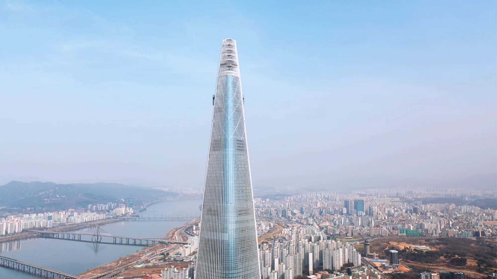 Lotte World Tower rises above the river and bridges of Seoul.