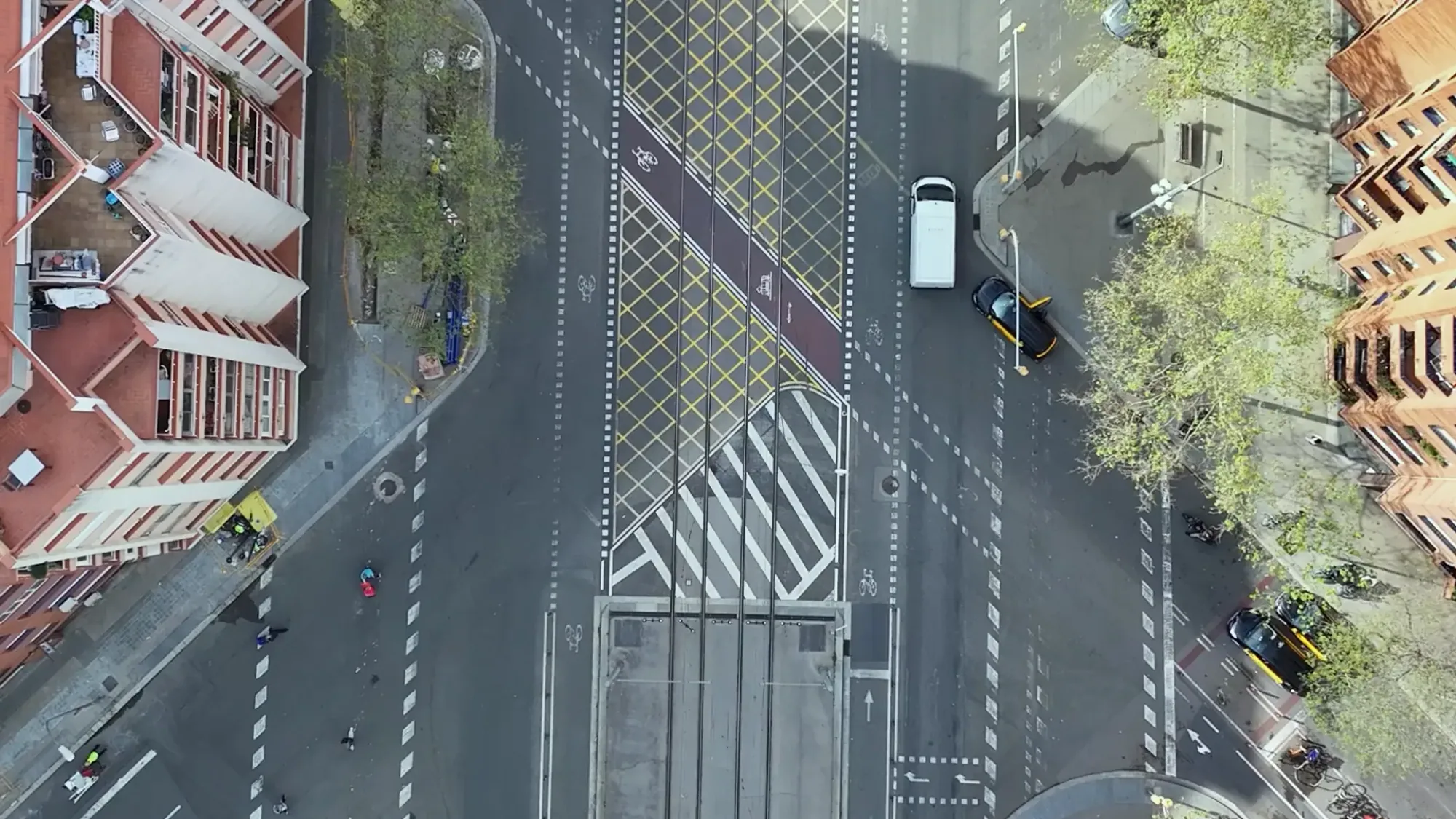 An overhead view shows a tram junction, cycle markings and brick apartment blocks in Barcelona.