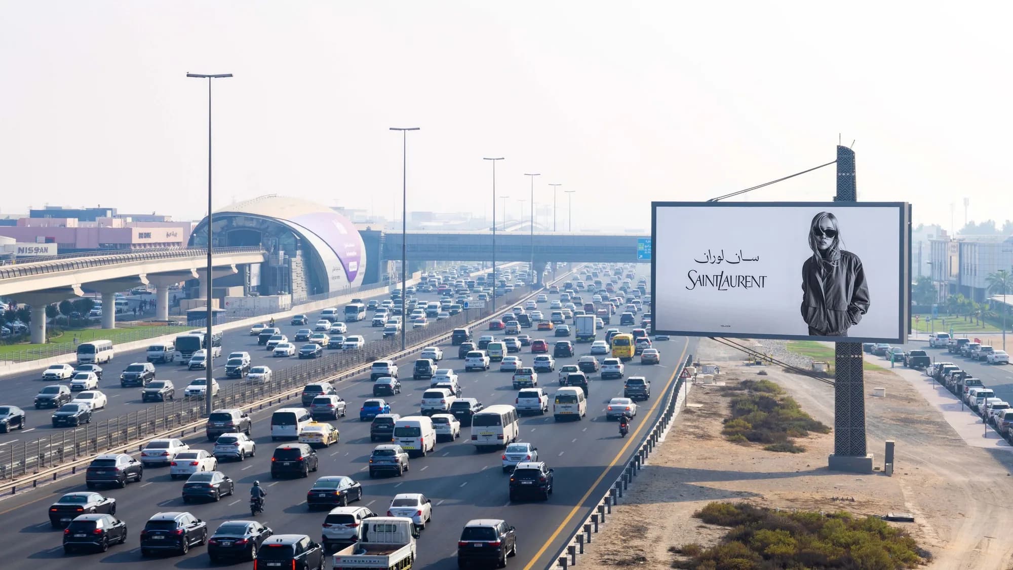 Billboard advertising in Dubai, in the UAE: a Saint Laurent board overlooks congested highway traffic beside an elevated metro line.
