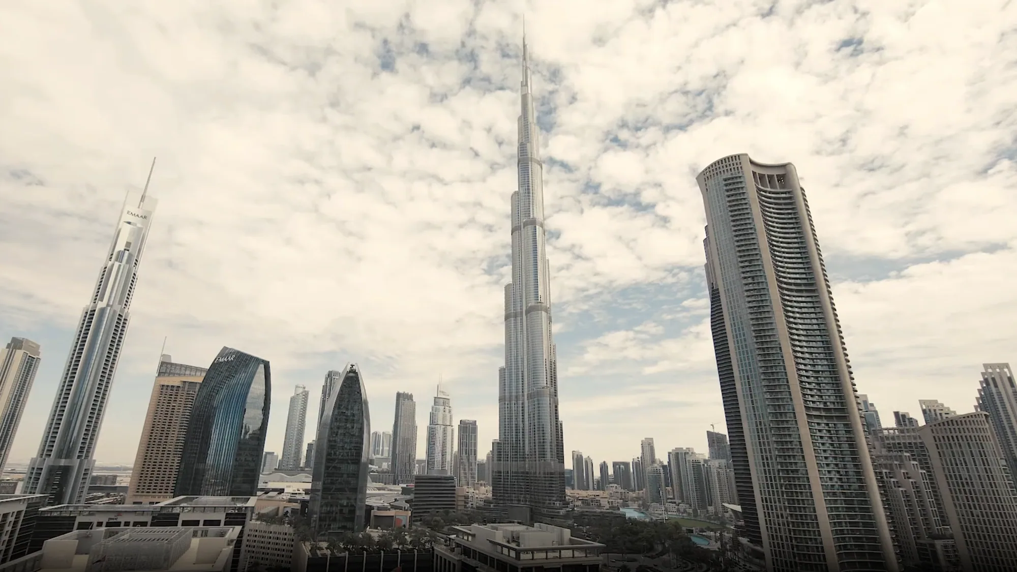 The Burj Khalifa rises among Dubai's towers under a cloudy sky.
