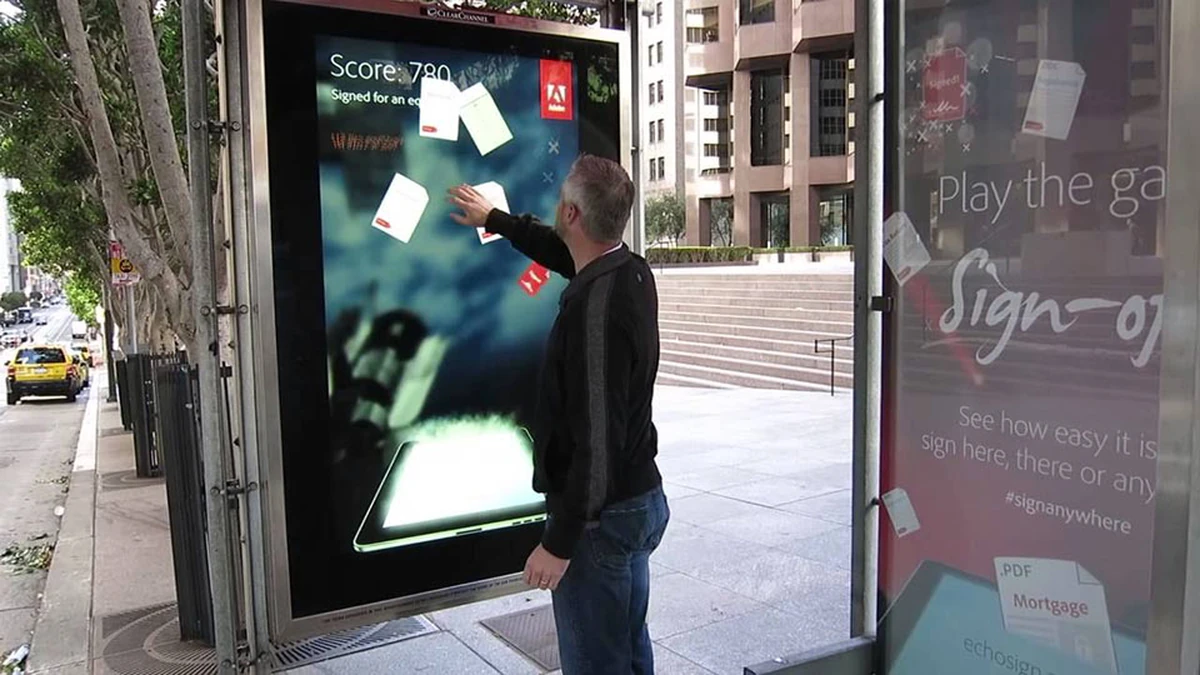 Interactive screen advertising: a man reaches into a street touchscreen showing documents and Score 780, beside an EchoSign panel that reads Play the game and #signanywhere.