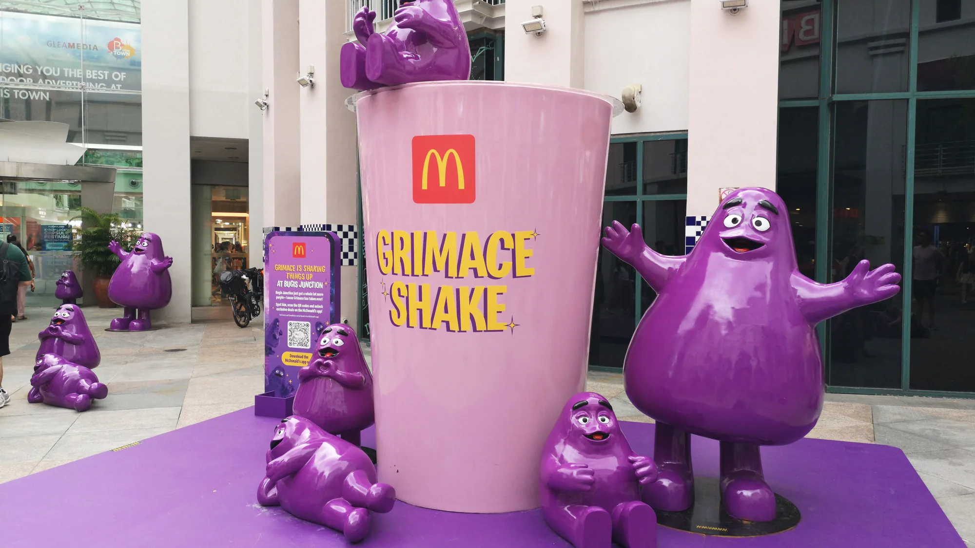 A brand activation popup: a pink Sculpted by Aimee kiosk draws a queue beside a matching branded car.