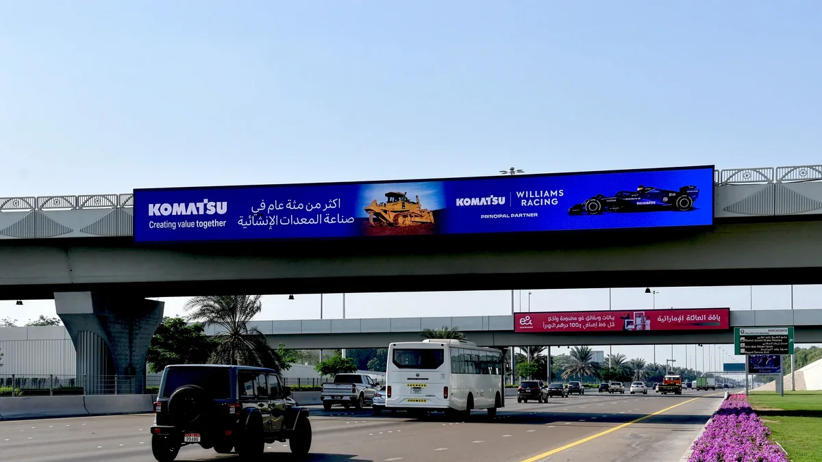 Bridge banner advertising: a Komatsu and Williams Racing banner runs along a highway overpass above traffic.