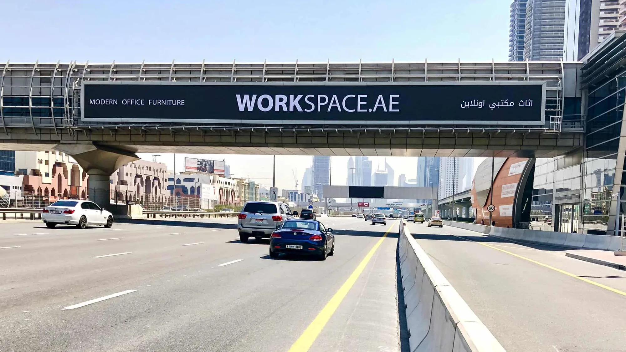 Bridge banner advertising in the UAE: a Workspace.ae banner for modern office furniture spans a pedestrian bridge over a highway.
