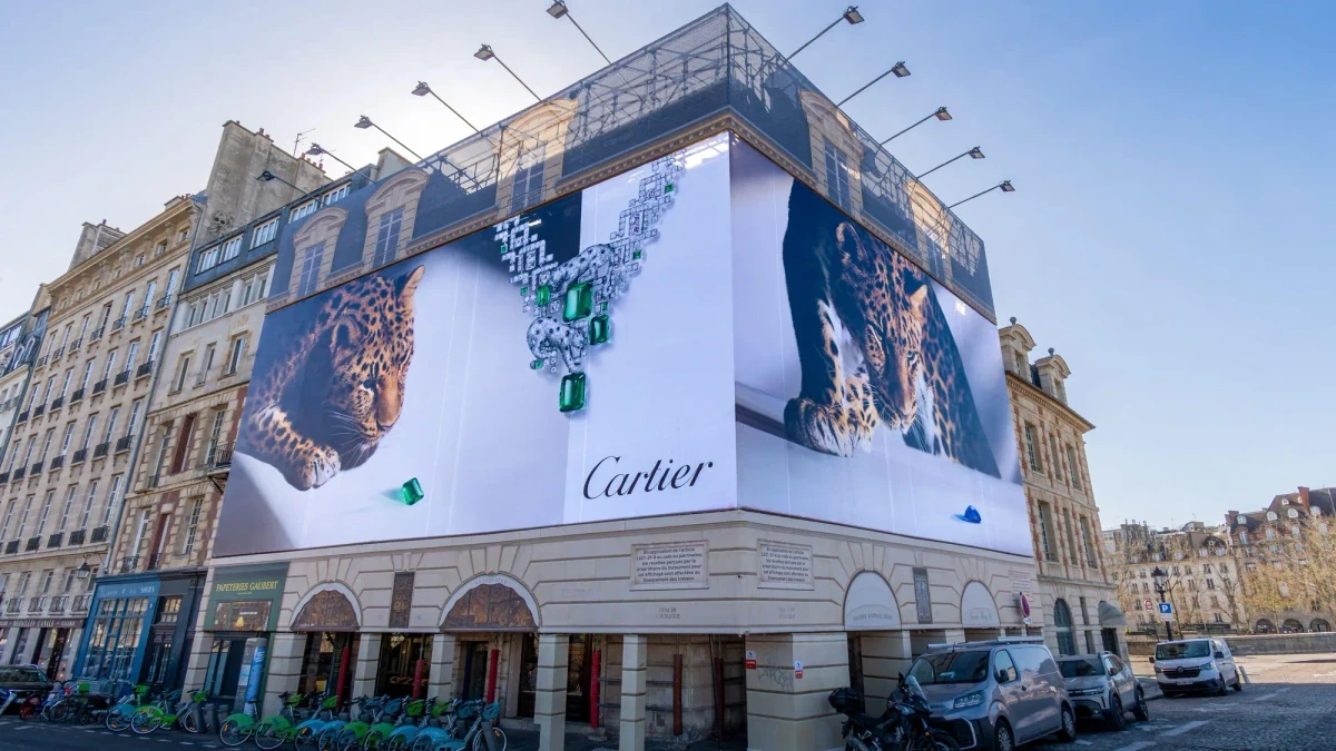 Building banner advertising in Paris, France: a Cartier banner of leopards and an emerald necklace wraps the corner of a building.