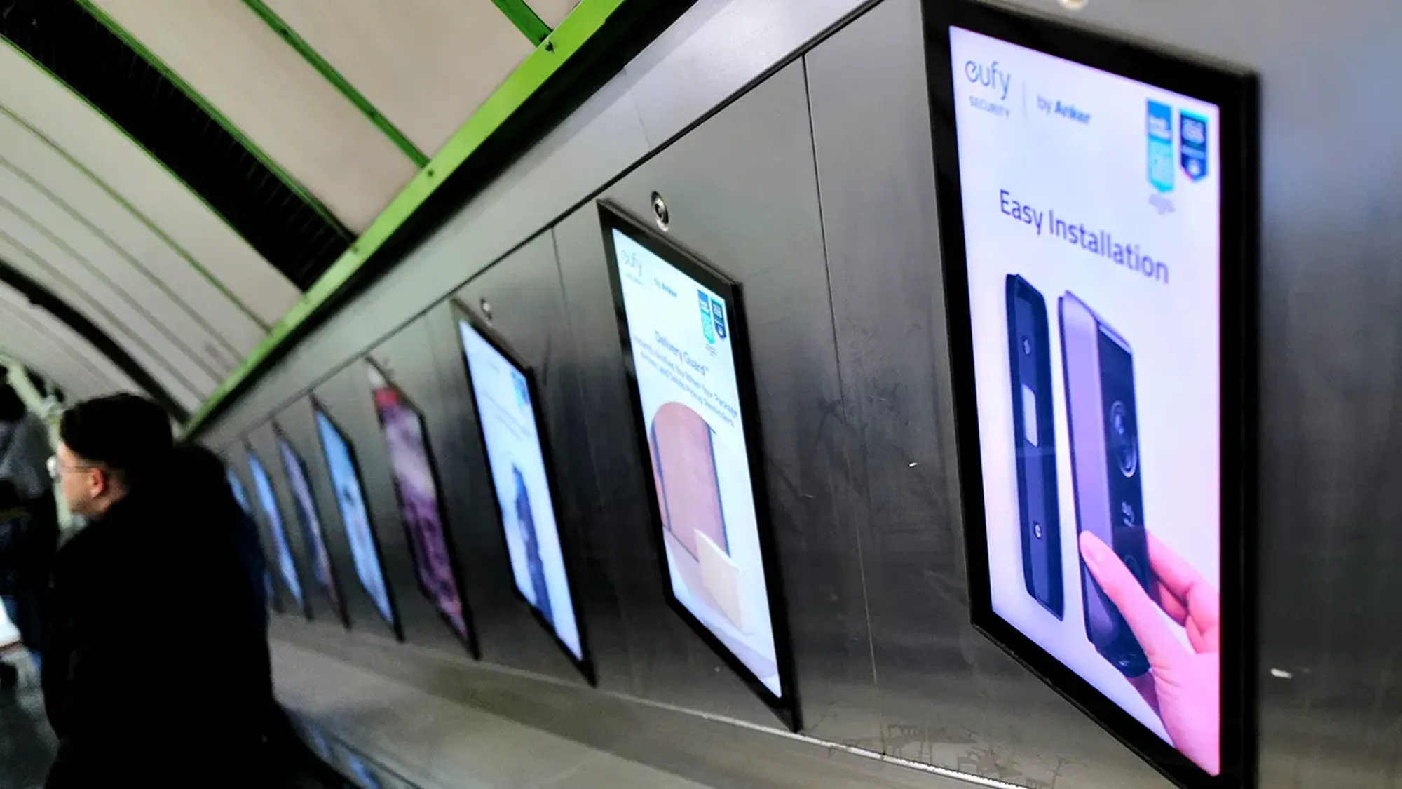 Digital underground advertising: a row of eufy by Anker screens lines the wall beside an escalator.