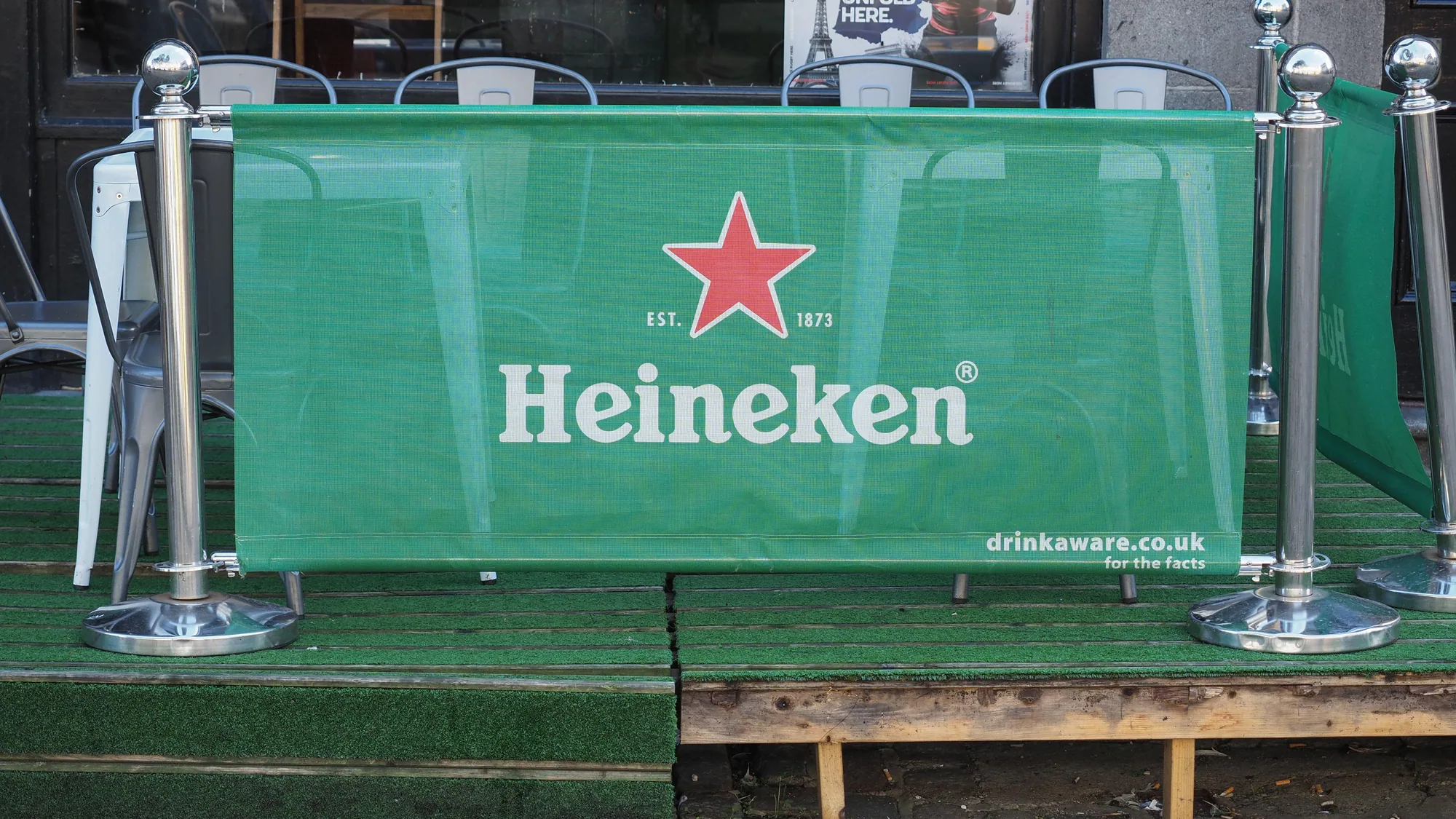 Large format mesh banner advertising: red and white banners for Baumit cover scaffolding on a building facade.