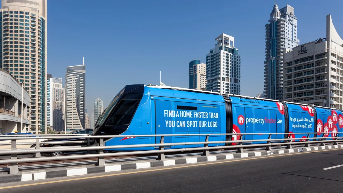 Tram wrap advertising in Dubai, in the UAE: a blue tram is wrapped for Property Finder against the city skyline.