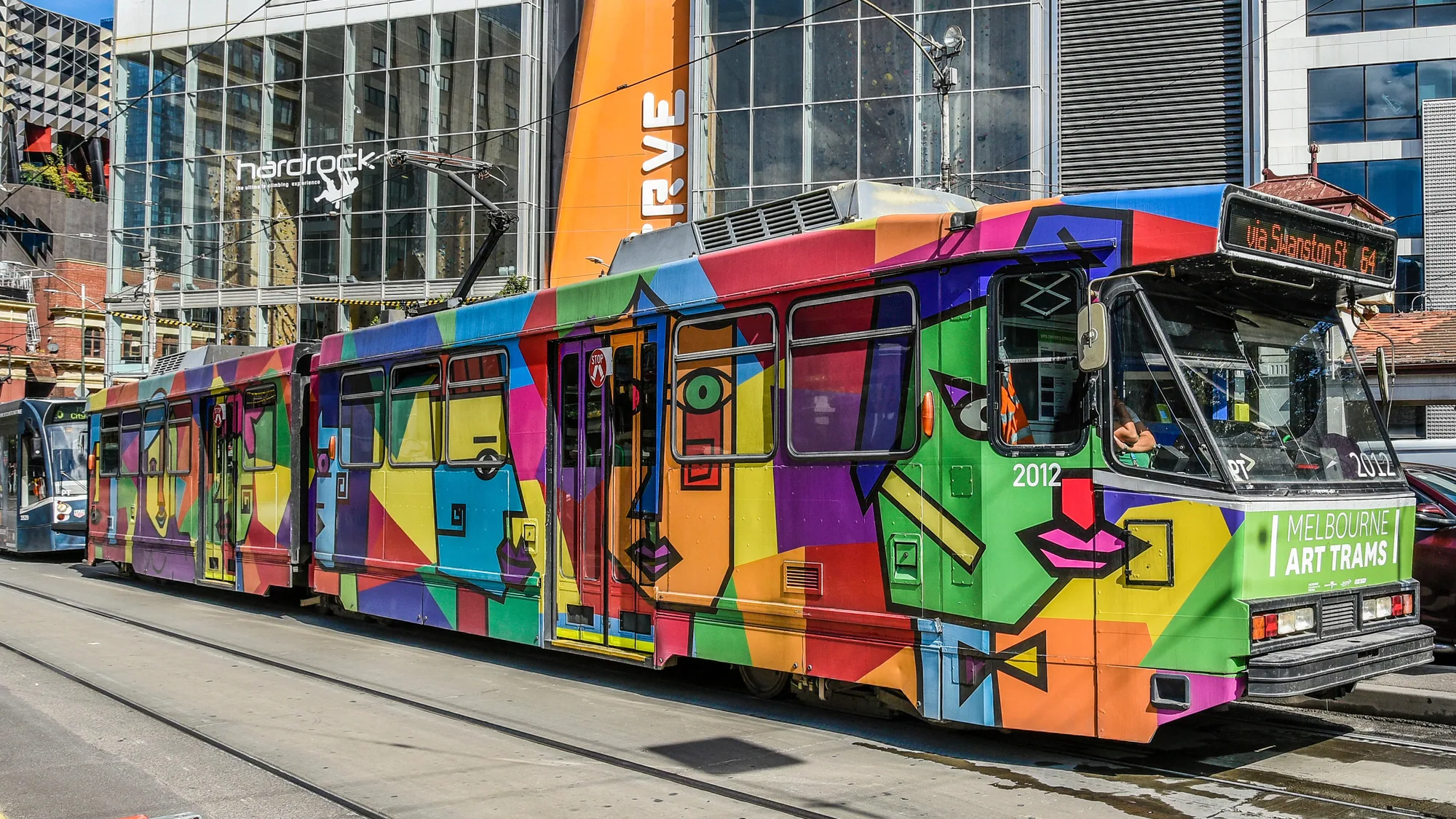 Tram advertising: painted portraits cover the side and windows of a purple and orange tram.