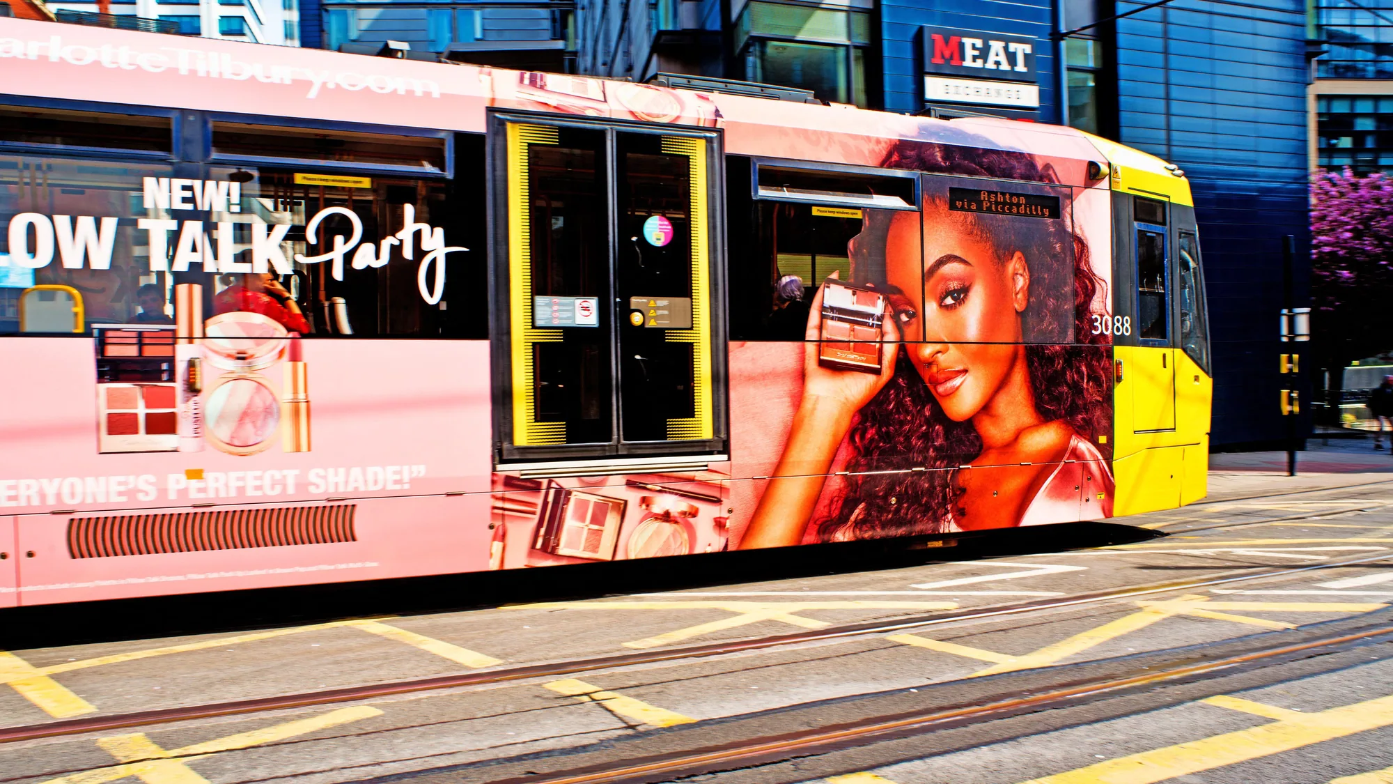 Tram wrap advertising: an AAMI advert covers the side of a blue and red tram on a city street.