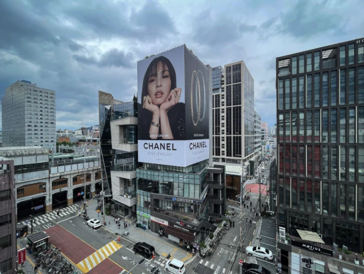 Building wrap advertising in Seoul, South Korea: a Chanel Fine Jewelry Coco Crush wrap covers a corner facade above a busy junction.